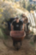 Picture of a man pushing a wheelbarrow maintaining a hiking trail.