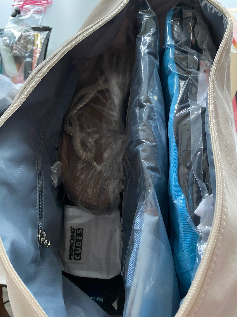 Open underseat bag showing clothes, shoes, and COMPRESSION CUBES packed.