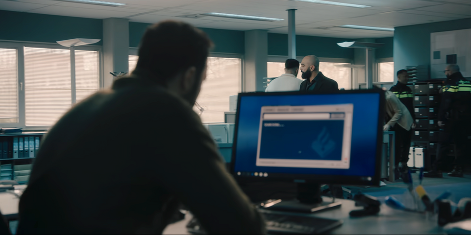 Nasrdin speelt in Het Gouden uur een scene achter de monitor en pc. politiebureau filmset