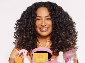 A Hispanic woman smiling while holding her hair products