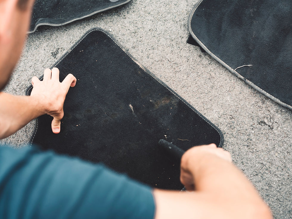 A main vacuuming a car mat