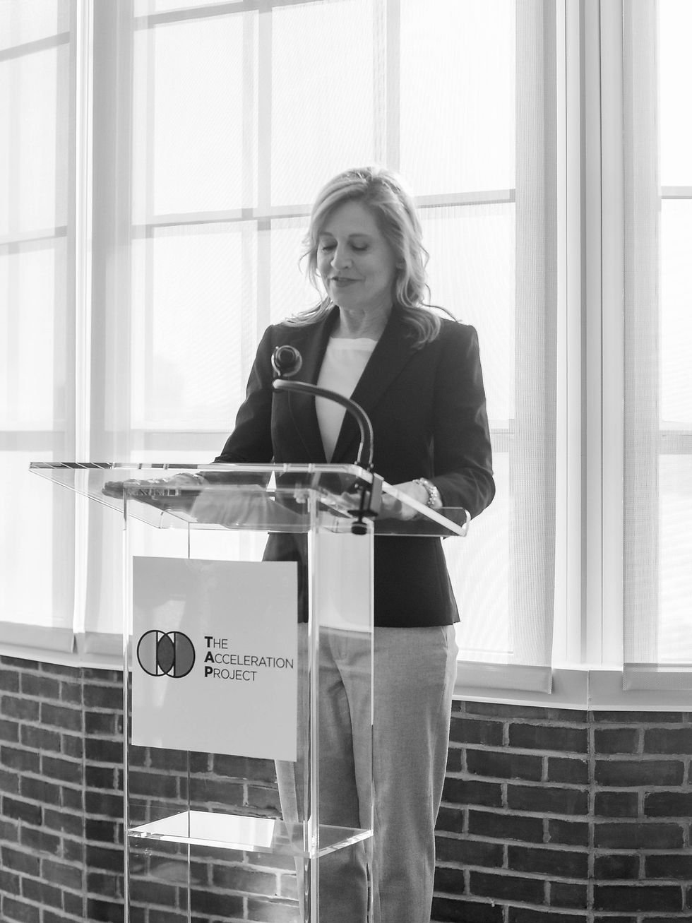 Black and white photo of TAP CEO Jane Veron standing at podium