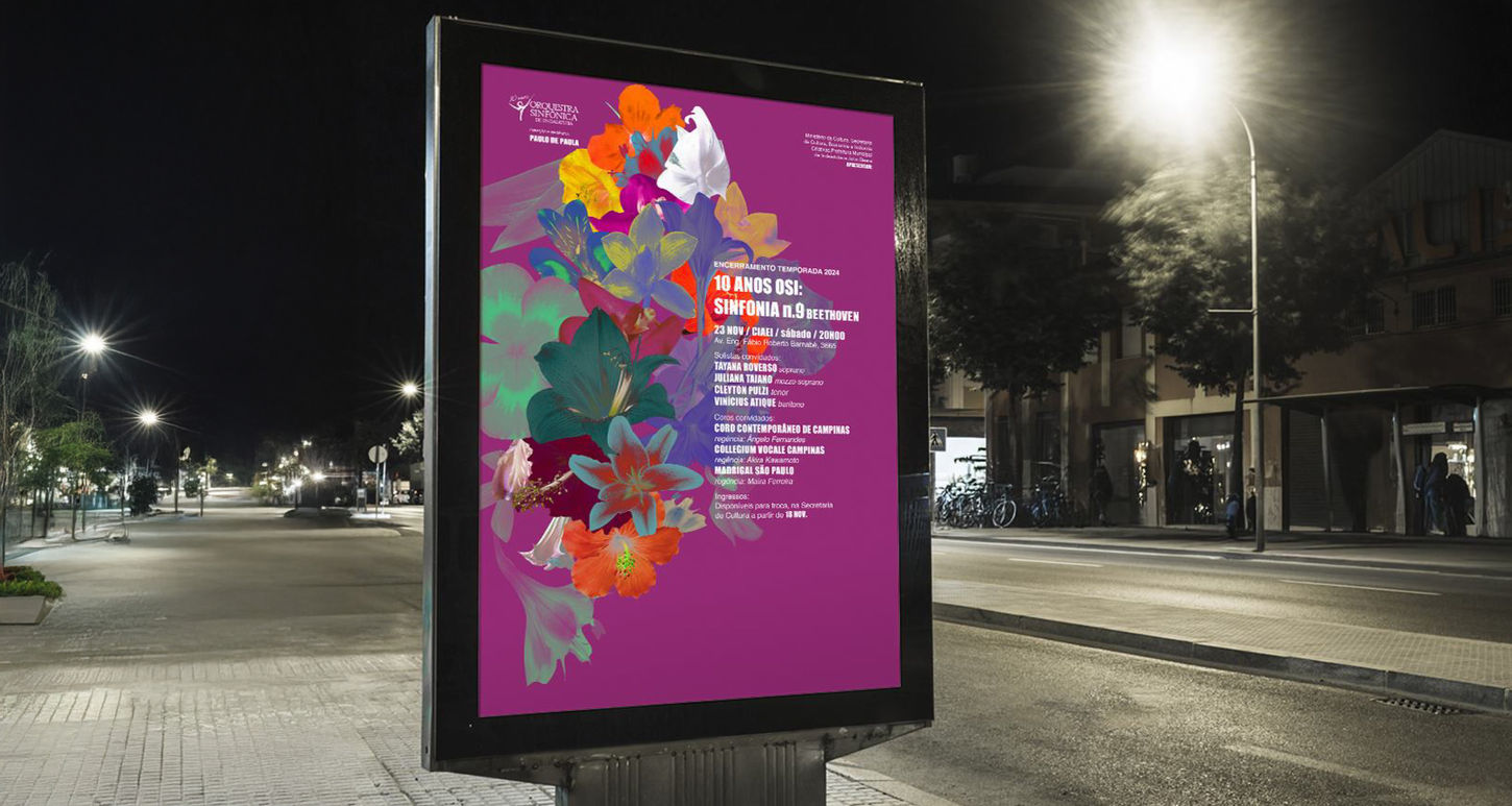 Foto de um cartaz grande em uma rua a noite. O cartaz tem um fundo magenta e um buque de flores desconstruidas. No cartaz existem informações escritas sobre o concerto.