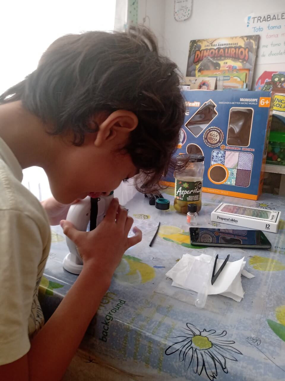 Niño explorando células y microorganismos en gota de agua salada con microscopio.