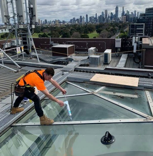 tradie installing glass on commercial building