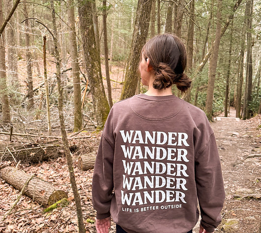Girl wandering outside in the woods wearing a Walk and WAdner repeating wander word crewneck sweatshirt.