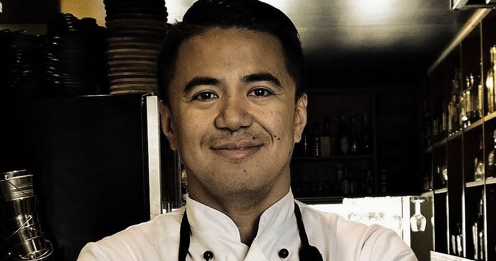 Chef Reverdy Pineda wearing a white chef's jacket and black apron in a professional kitchen in Oslo, Norway.