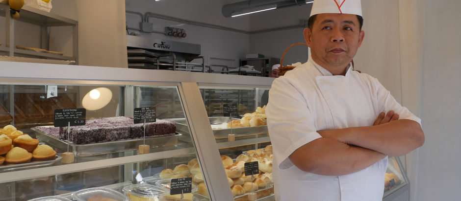 Romeo Mendoza inside his Filipino bakery in Milan surrounded by freshly baked pandesal, ensaymada, and traditional Filipino bread products serving the Filipino community in Italy.