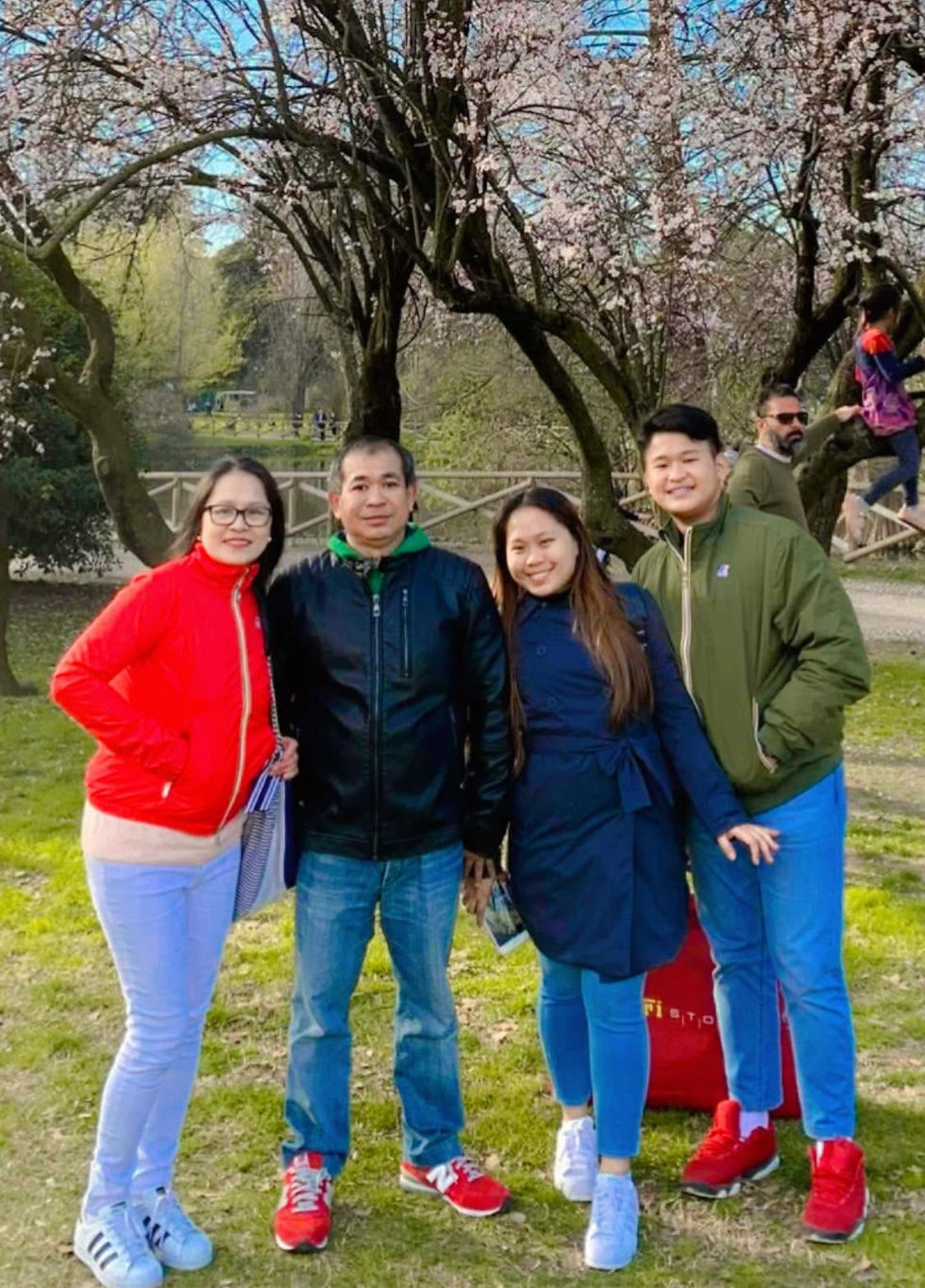 Mercy and her family pose pose on the lawn at Piazza dei Miracoli in Pisa, with Pisa Cathedral and the Leaning Tower visible behind them.