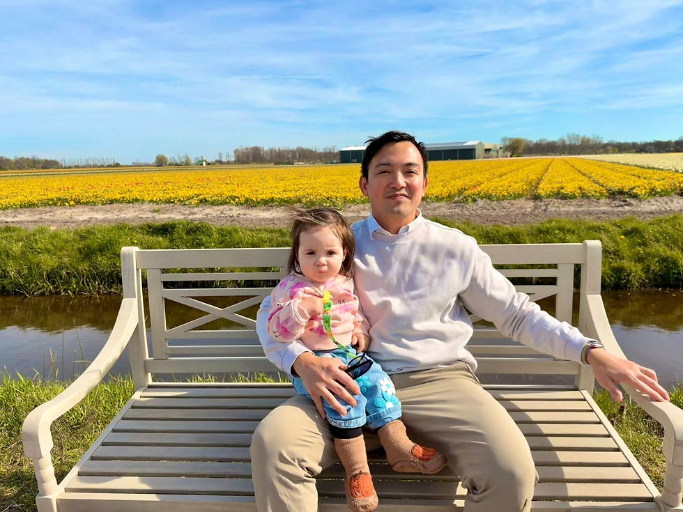 Chris Sta. Brigida-Kopp shares a quiet moment with his daughter on a bench overlooking blooming tulip fields in the Netherlands, reflecting family, legacy, and belonging.
