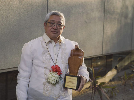 Gene Alcantara, Filipino writer, translator, and literary scholar, poses with a literary award while wearing a traditional Barong Tagalog.