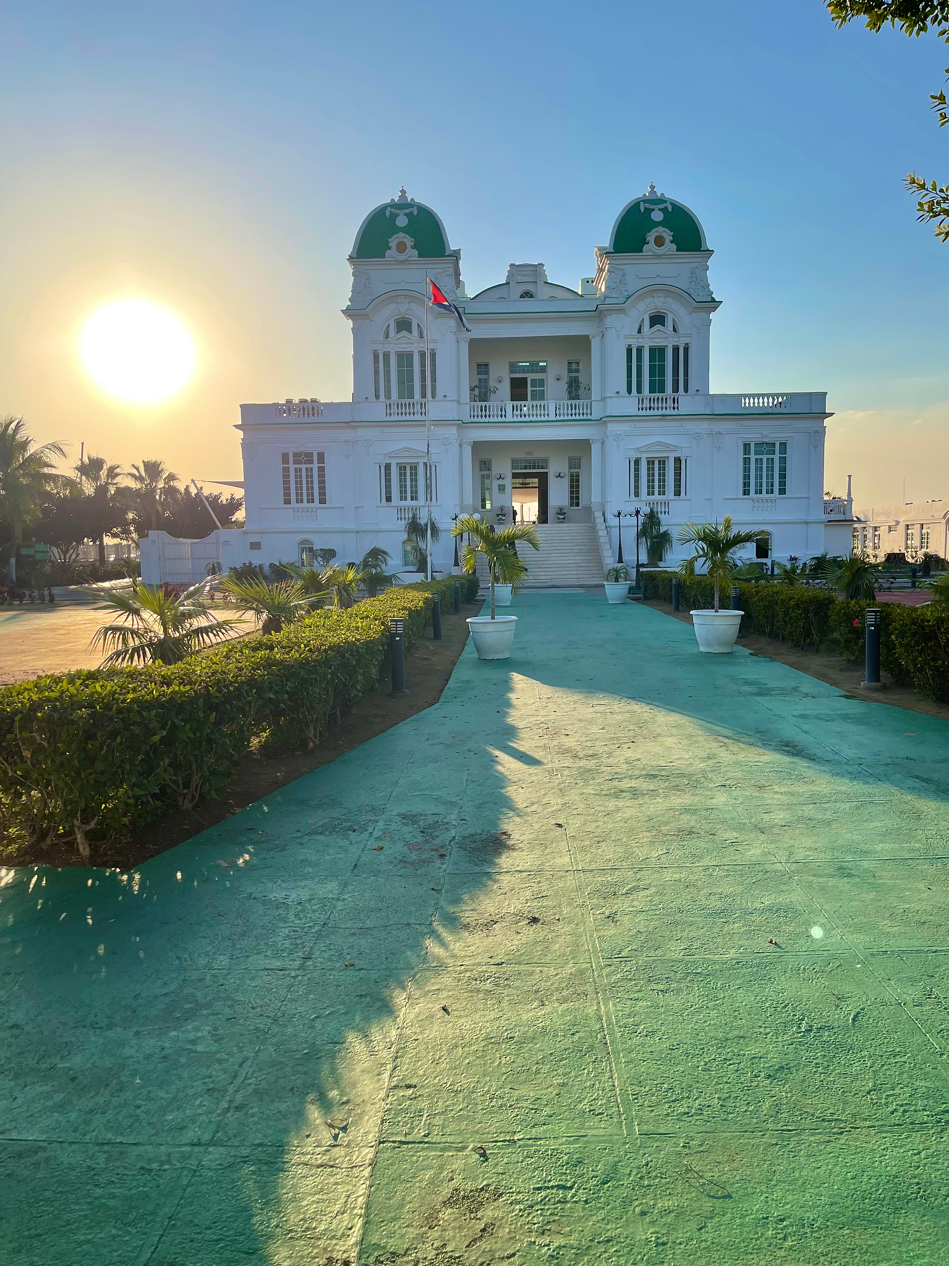 Grand historic Cuban building illuminated by the setting sun and surrounded by palm trees