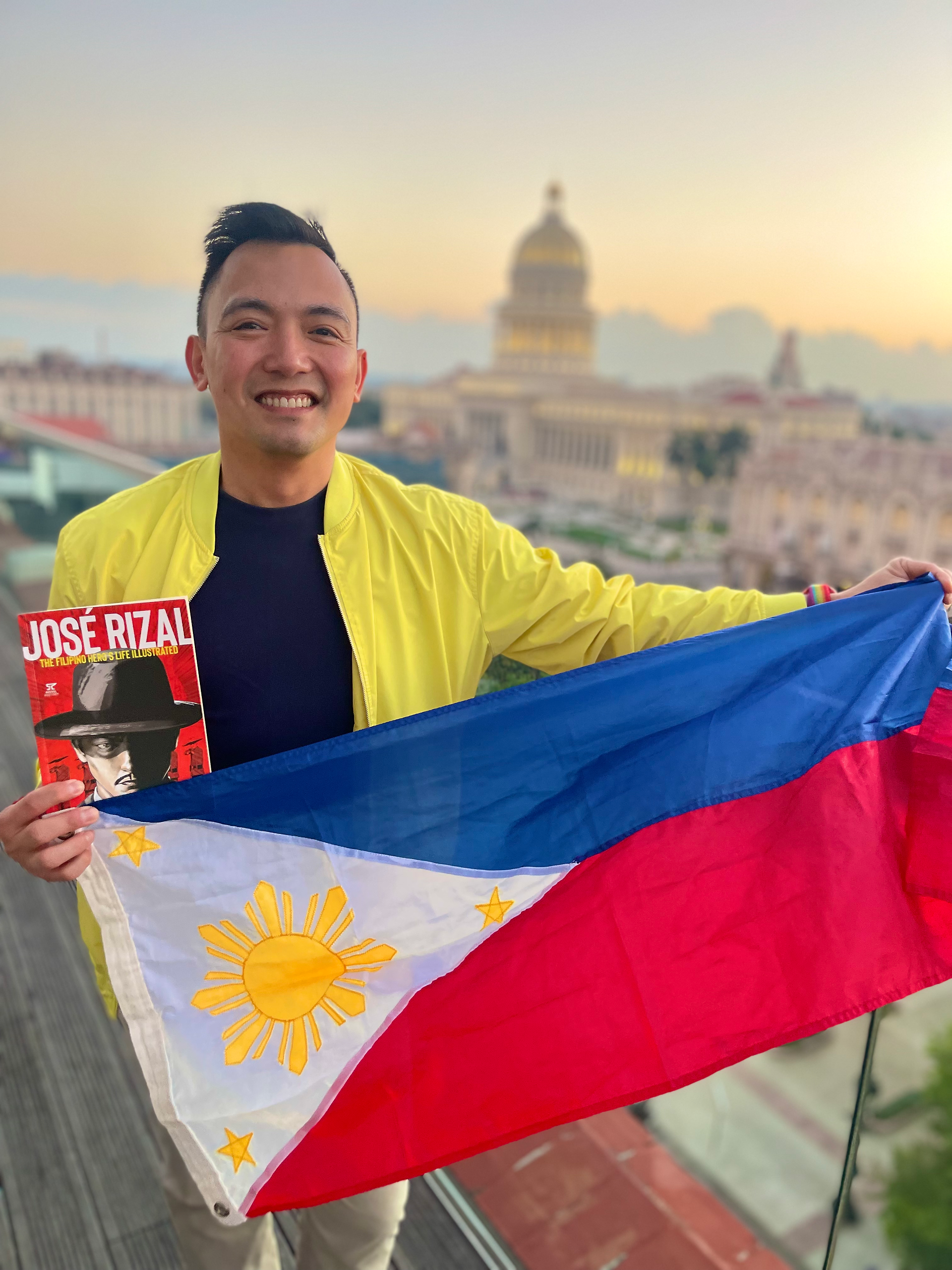 Chris Sta Brigida-Kopp holding the Philippine flag and a José Rizal book overlooking Havana, Cuba
