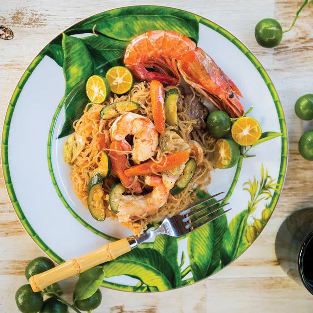 Filipino pancit noodles with shrimp, vegetables, and calamansi served on plate showcasing Filipino cuisine