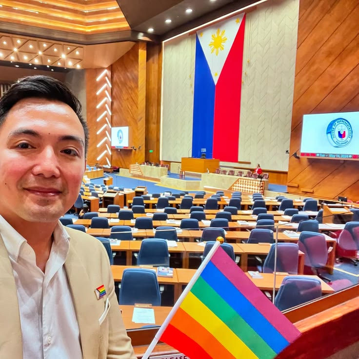Chris Sta. Brigida-Kopp holds the Philippine flag during at the House of Representatives, celebrating Filipino identity and global LGBTQIA+ advocacy.