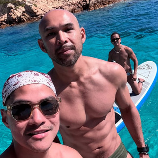 Wil abd Ben enjoy a sunny day on turquoise waters, posing in the foreground during a paddleboarding excursion.