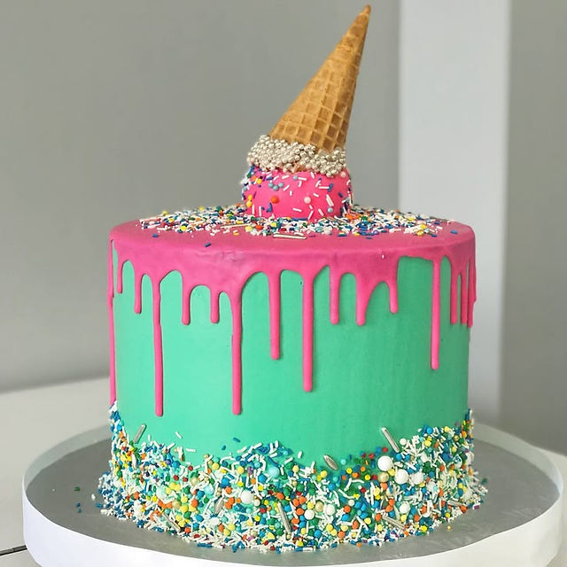 Colorful turquoise cake with pink drip icing, sprinkles and an upside-down ice cream cone