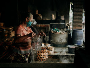 Elderly woman cooks over a fire at home