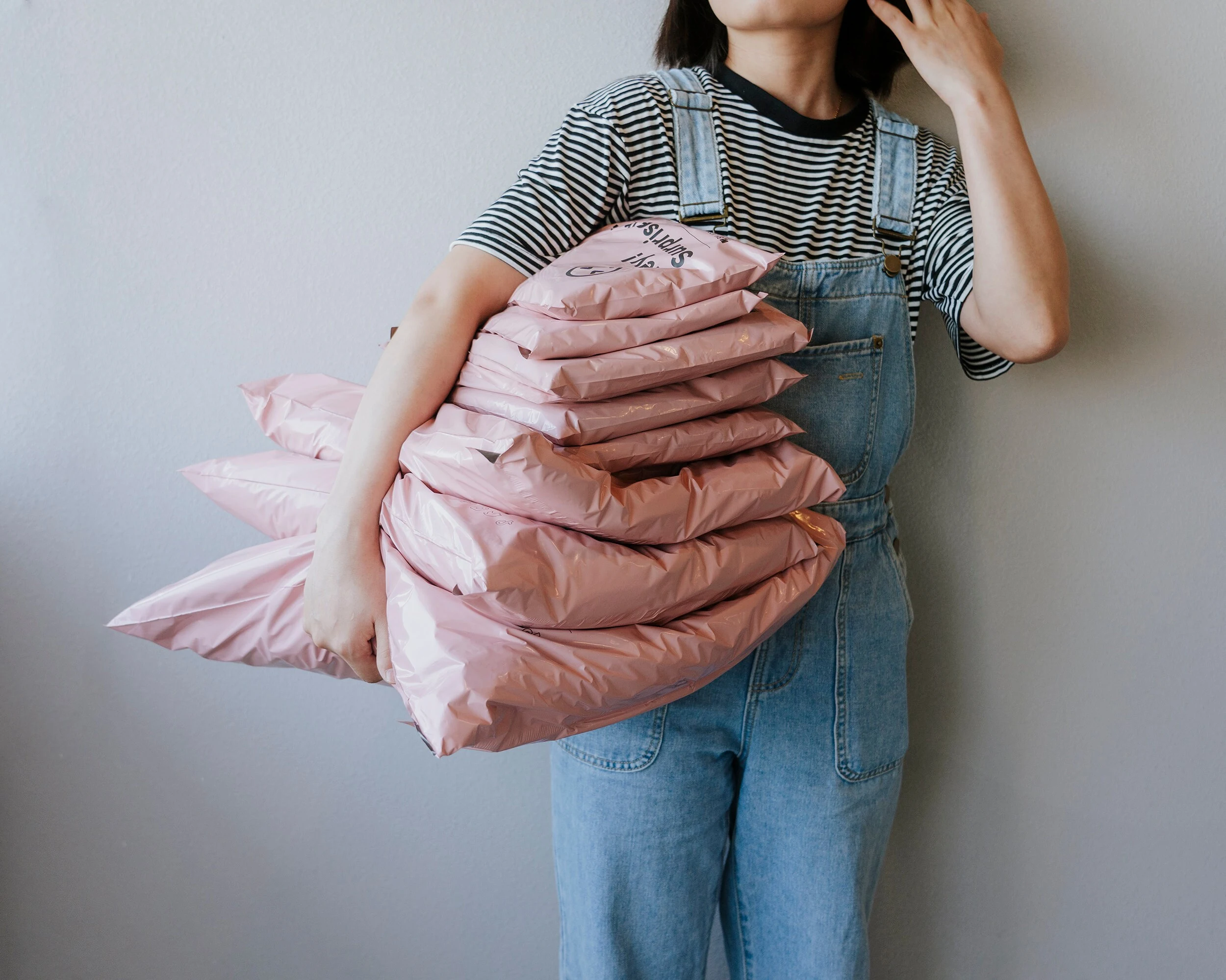 A girl with stack of poly mailer shipping envelopes