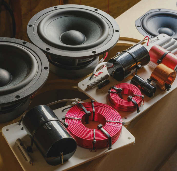 Router cutting speaker enclosure at workbench and finished CSS Audio speaker on stand in home listening room