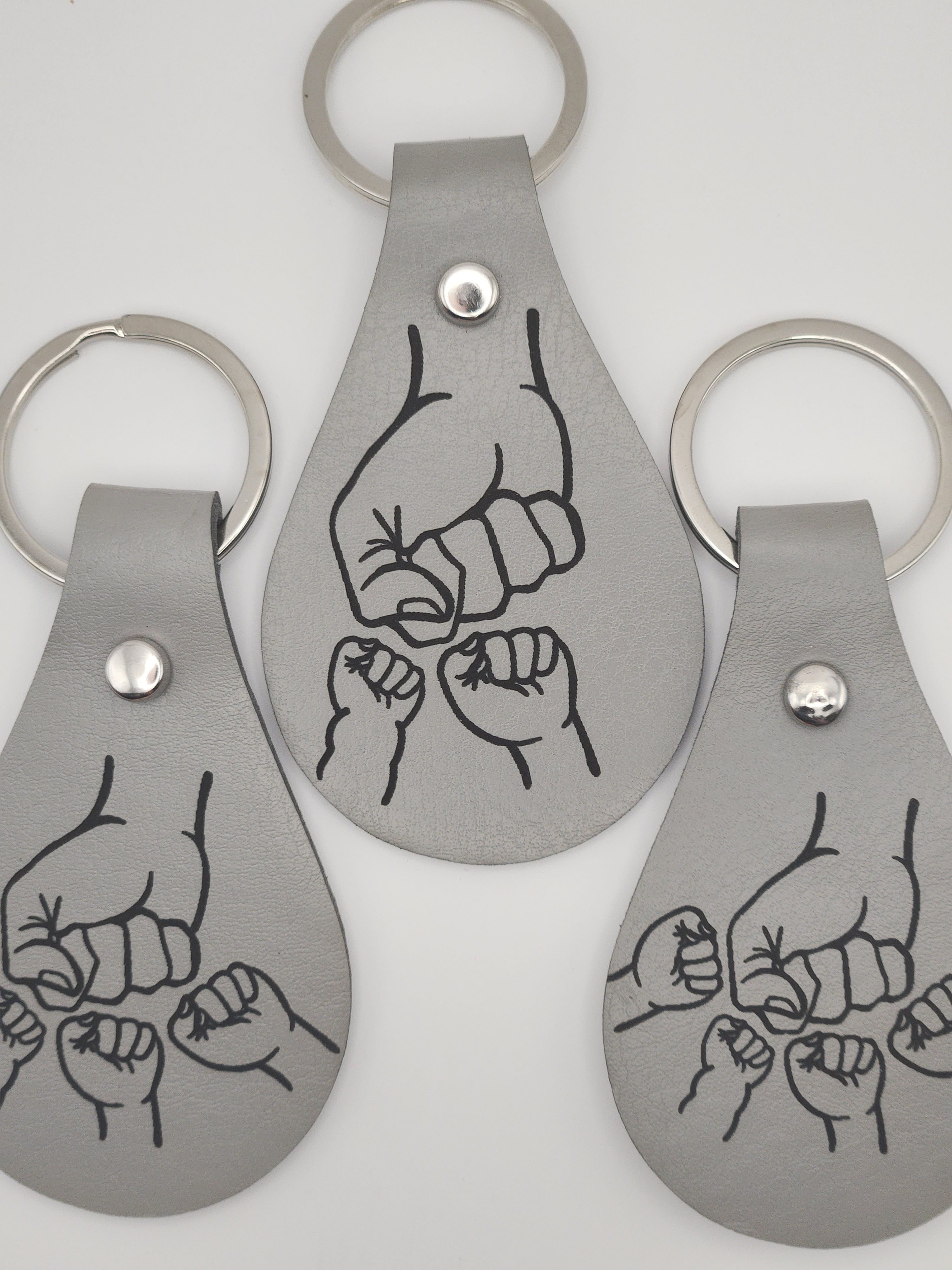Grey keychains with family fist bump designs