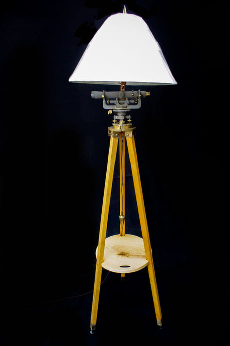 A lamp created with a brass antique surveyors scope with a black background