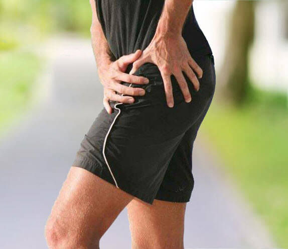 Man with sciatica holding his hip in pain