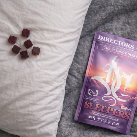 Top-down view of fast-acting sleep gummies on a pillow next to a Directors Cut Sleepers bag for deep, restful sleep