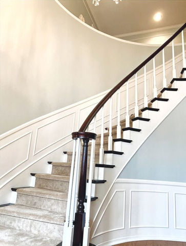 Finished staircase with matte walls, white wainscoting, and satin-stained handrail in Murrieta home