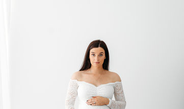 pregnant woman in a white dress holding her bump