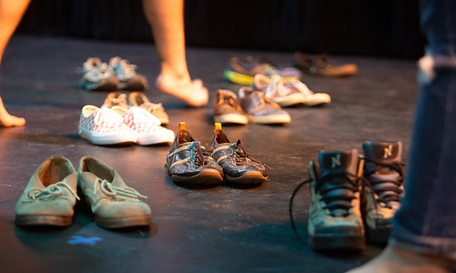 Ten pairs of different types of shoes spread out onstage during a performance of 'The Magic in this Soul'