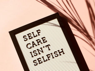 A motivational graphic with the words "SELF CARE ISN'T SELFISH" arranged in a descending stack, with "SELF" in the largest text at the top.