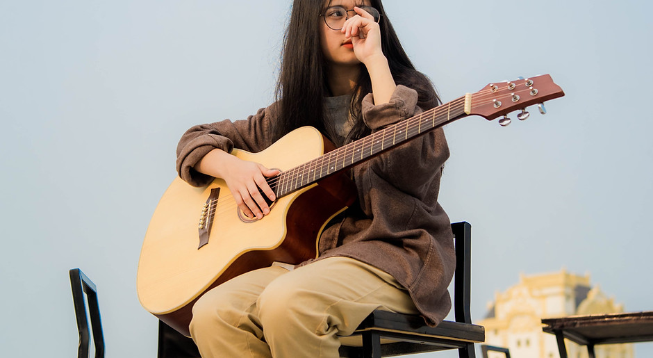 woman-holding-guitar-while-sitting-21180
