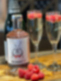 Sparkling wine cocktail with raspberry gin and fresh raspberries in a glass
