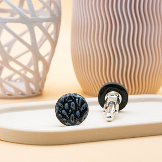 Black round cufflinks with an embossed flower design and graphite accents, paired with silver backers. These elegant cufflinks blend sophistication with refined taste, ideal for the modern gentleman. Make a statement on any occasion.