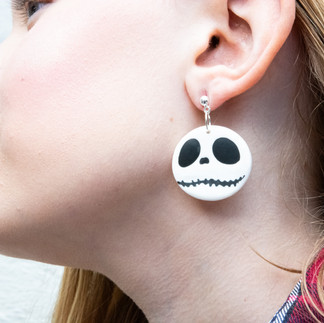 A blonde girl wearing a pair of Jack Skellington head round dangle earrings from A nightmare before Christmas. These earrings are from the Cat Creations Halloween 2024 Collection.