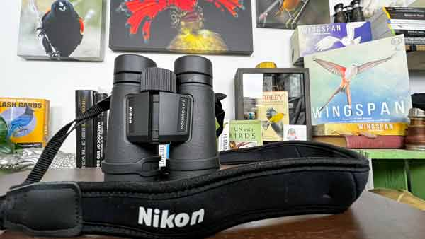 a pair of nikon binoculars sits in front of a background filled with bird images