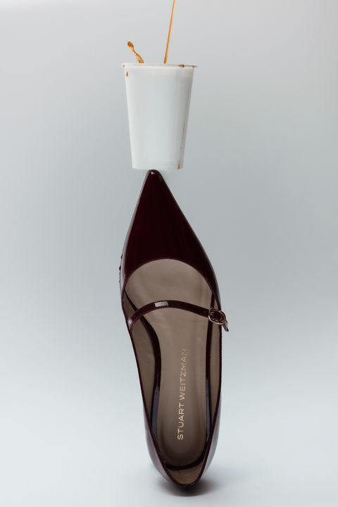 still life image of a high heel shoe with a cup of coffee balanced on top.