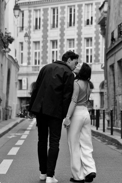 A couple kisses while walking down the streets of Paris.