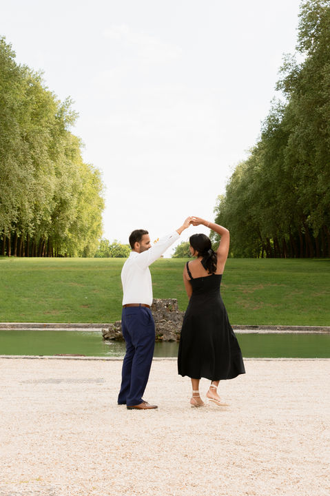 A man twirls a woman in a grand garden in the French countryside.