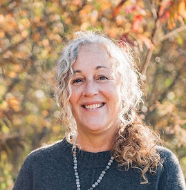 A woman with her arm around her daughter's shoulder; both wearing tie dyed t-shirts