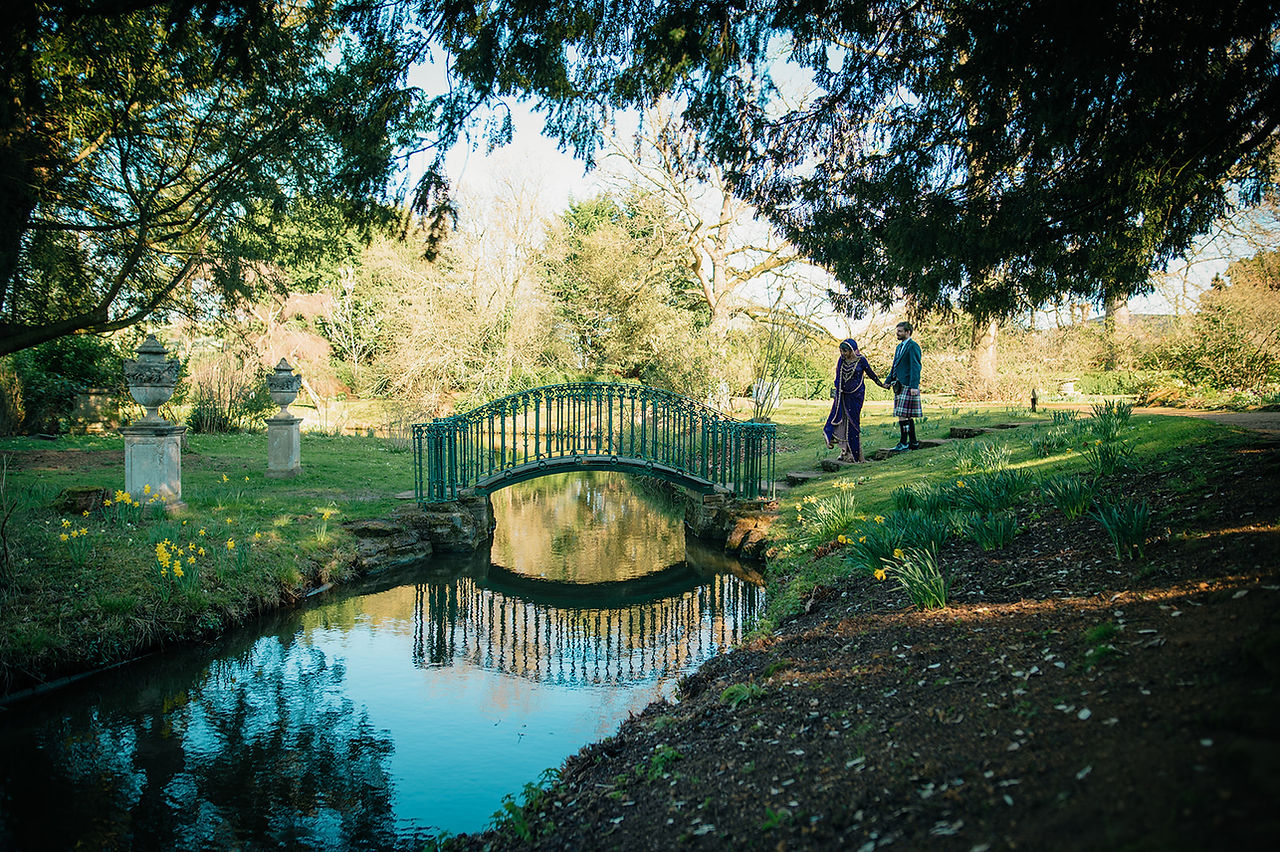 Bride leads groom over ornate bridge in Shutleworth Swiss Gardens.