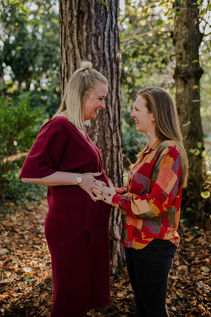 A lesbian couple cradle their baby bump during a maternity photoshoot with Tara Gillen Photography