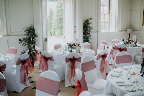 Elegant white and red wedding breakfast decor indoors at Chicheley Hall wedding venue.