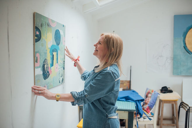 A businesswomen hangs one of her painting on the wall during her branding photography photoshoot in Bedford