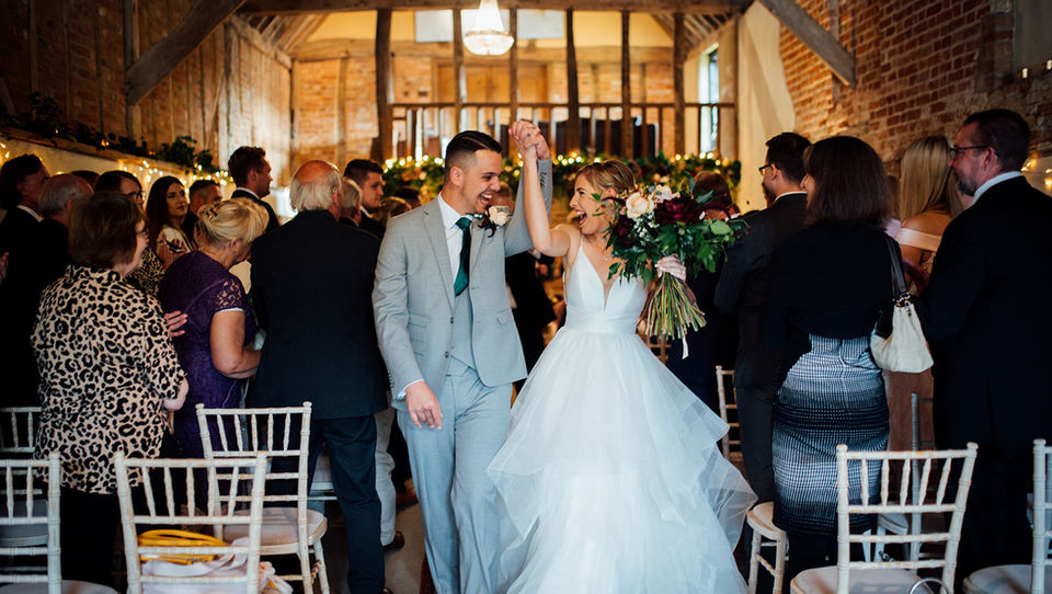 A bride and groom walk down the aisle at their rustic wedding at the barn at Brookend Green Farm captured by Tara Gillen Wedding Photographer