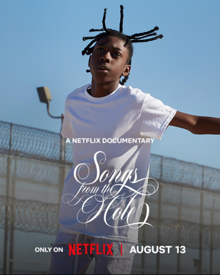 Young person in white shirt stands in front of a fence under a clear sky. Text reads "Songs from the Hole" and release date "August 13." Netflix.