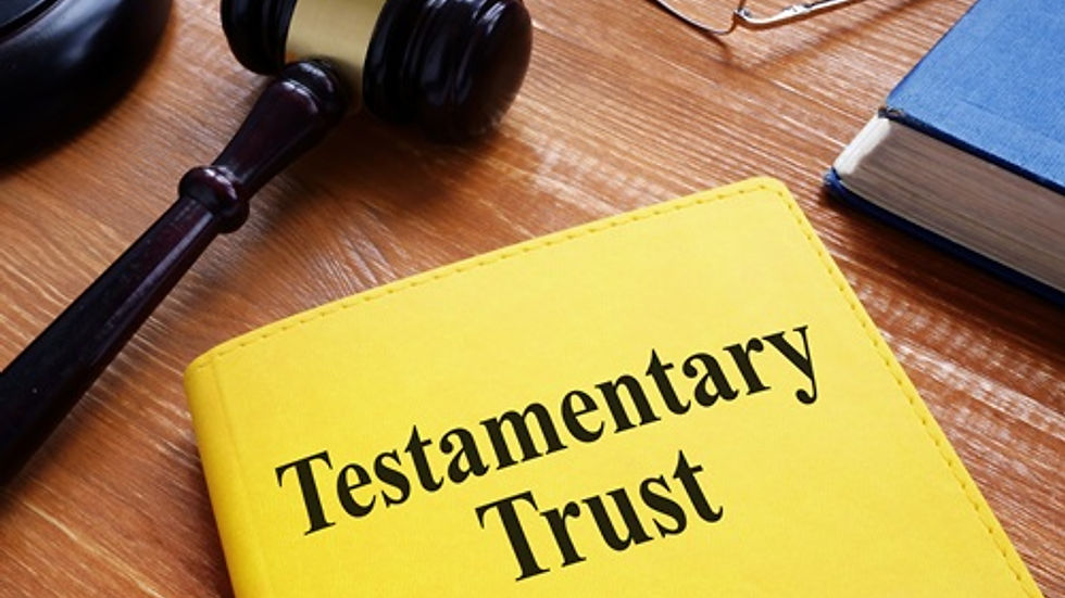 Yellow book with "Testamentary Trust" text on a wooden table, beside a gavel. A pair of glasses and papers are in the background.