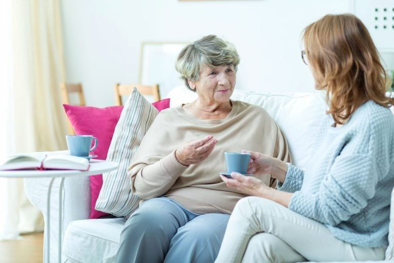 2 women chatting with a cup of tea, on the sofa