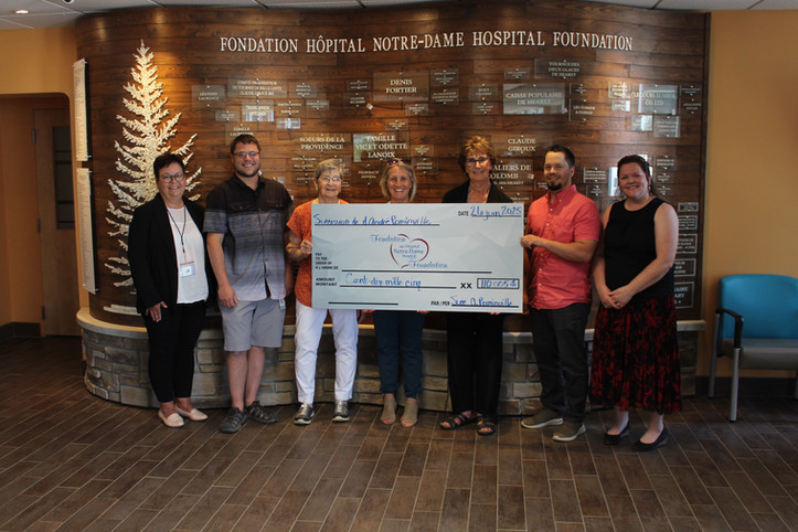 Sept personnes tiennent un chèque grand format.